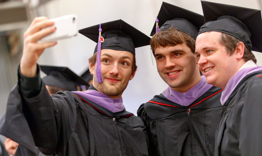 Students taking selfie in graduation robes